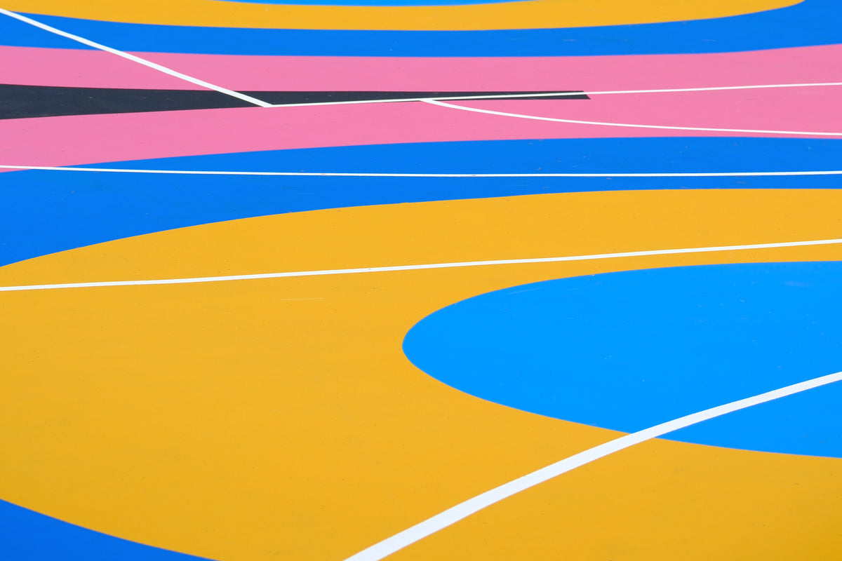 Colorful acrylic netball and basketball court surface with yellow, blue, and pink patterns