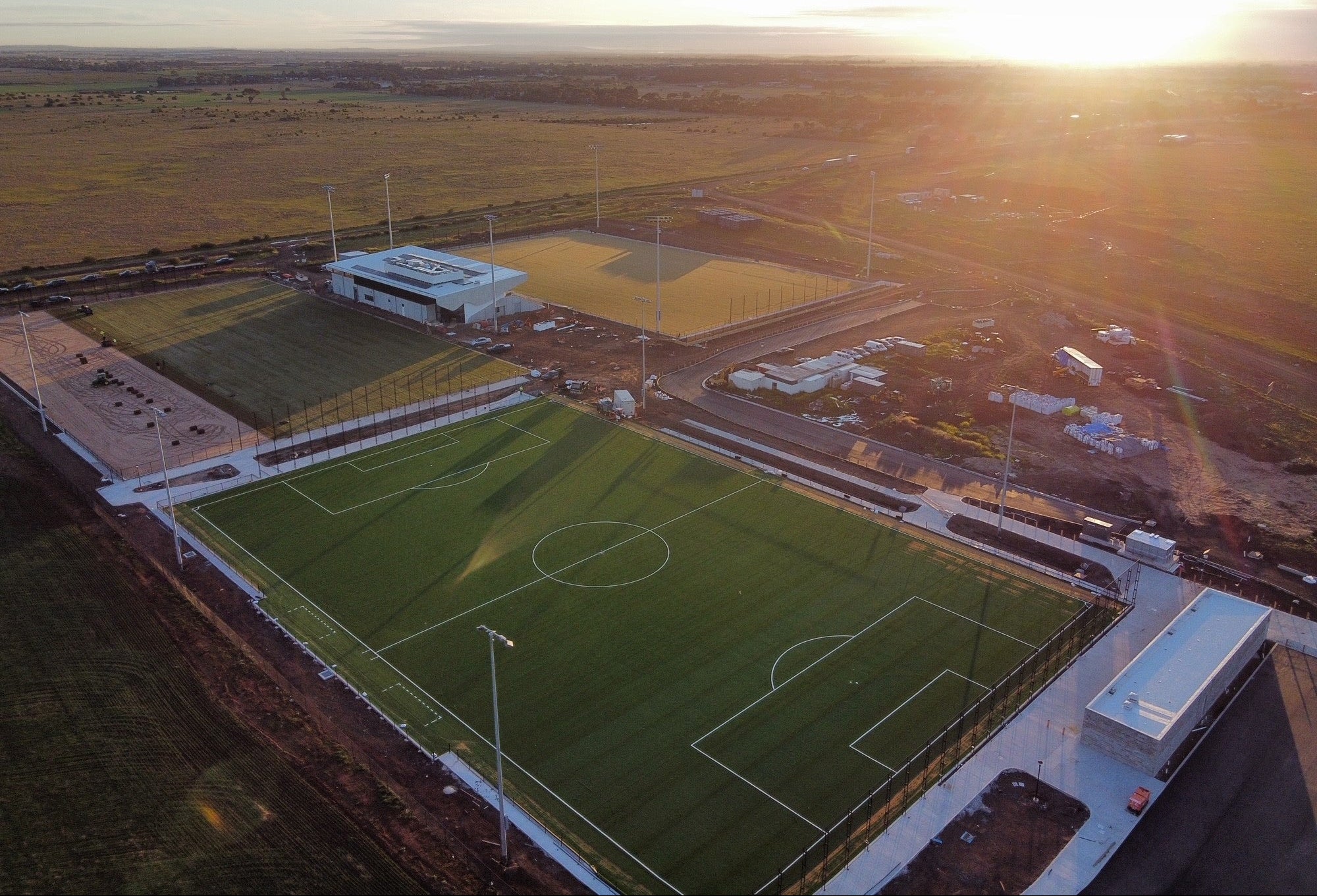 Aerial view of synthetic turf FIFA soccer pitch in stadium precinct at sunset
