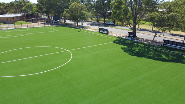 Aerial view of a synthetic turf soccer field with clear white markings and sideline benches