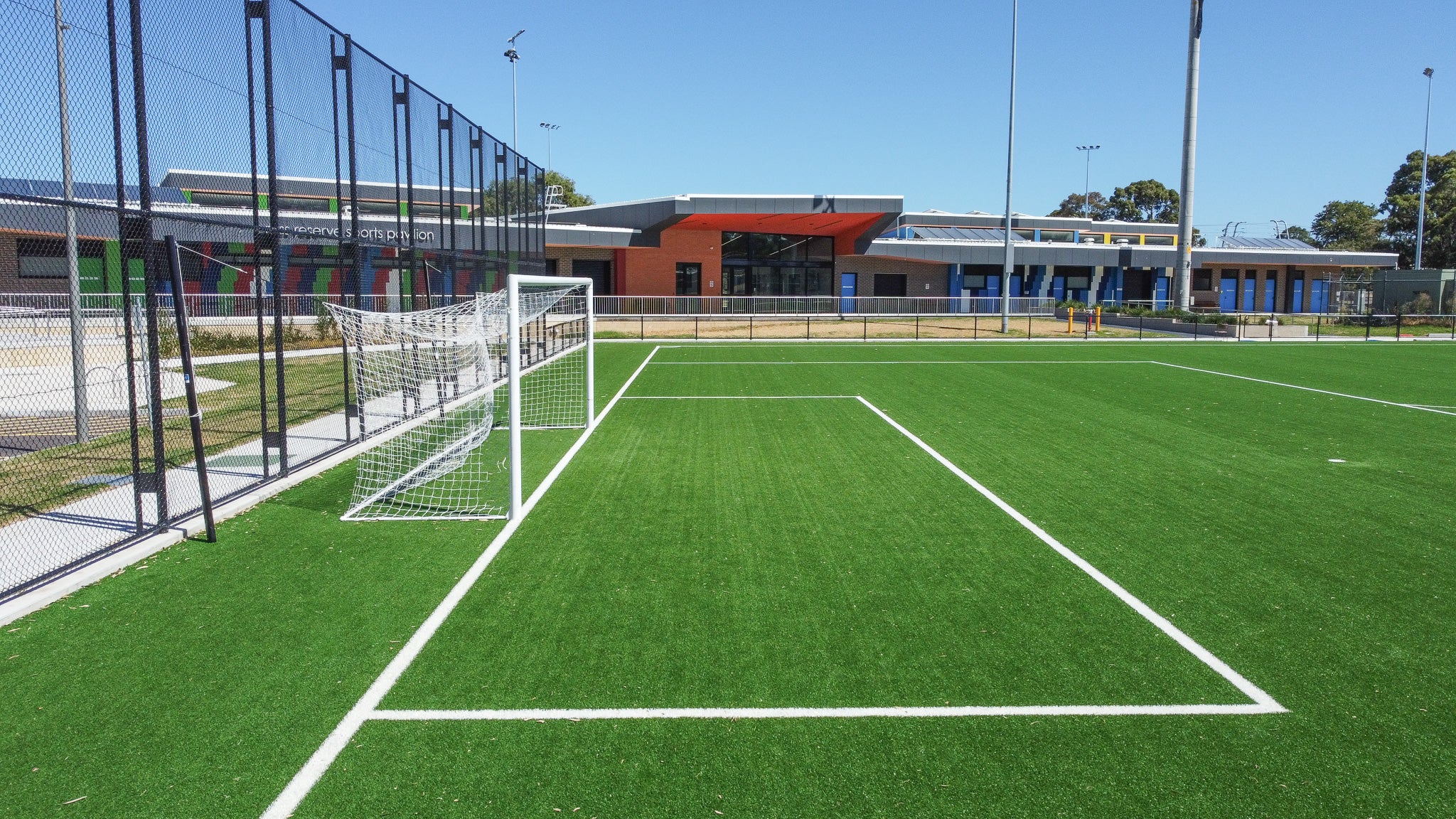 Synthetic soccer field with goalposts, bright green artificial turf, and sports pavilion.