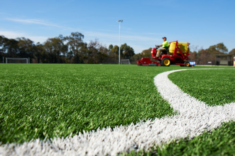 Synthetic turf sports field maintenance with machinery on green artificial grass