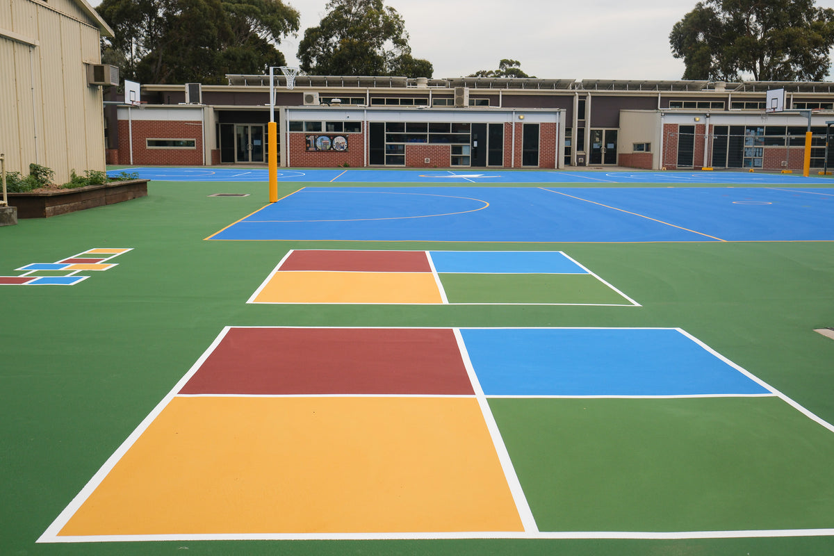 Colorful synthetic turf sports courts at school, featuring painted surfaces and game lines.