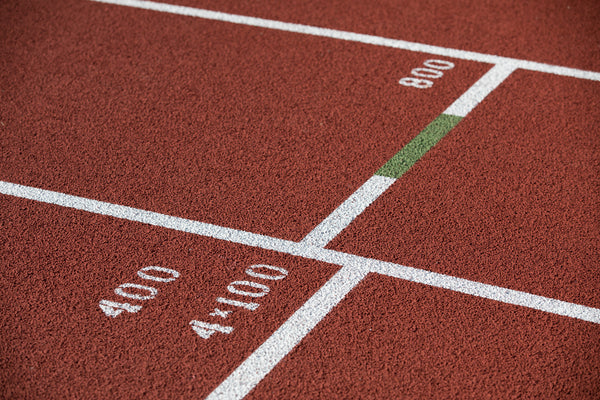 Red synthetic running track with white lane markings and green start line accents