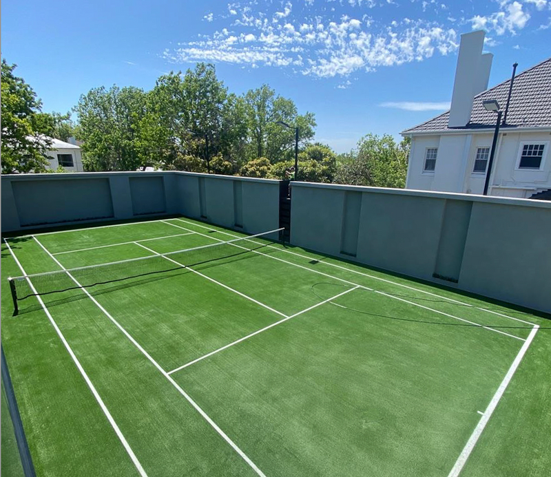 Outdoor synthetic turf tennis court with green artificial grass and white line markings